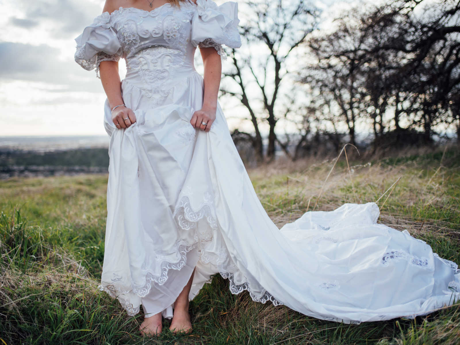 Close up of bride holding up skirt of wedding gown that once belonged to her mother that passed from cancer