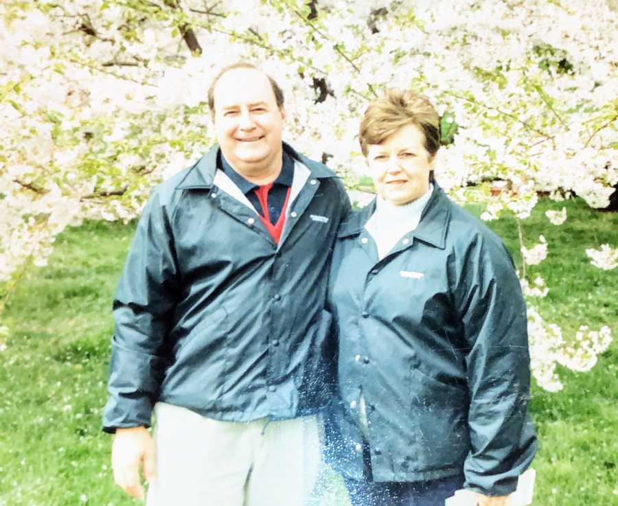 Couple who met at Steak 'n Shake in 1962 smile arm in arm in front of cherry blossom tree