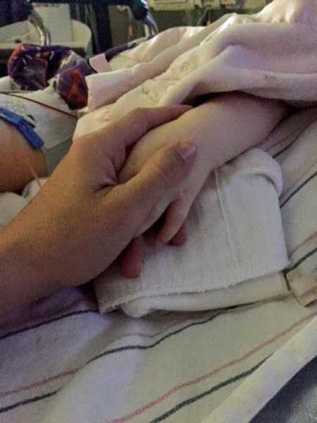 Mother holding toddlers hand after open heart surgery