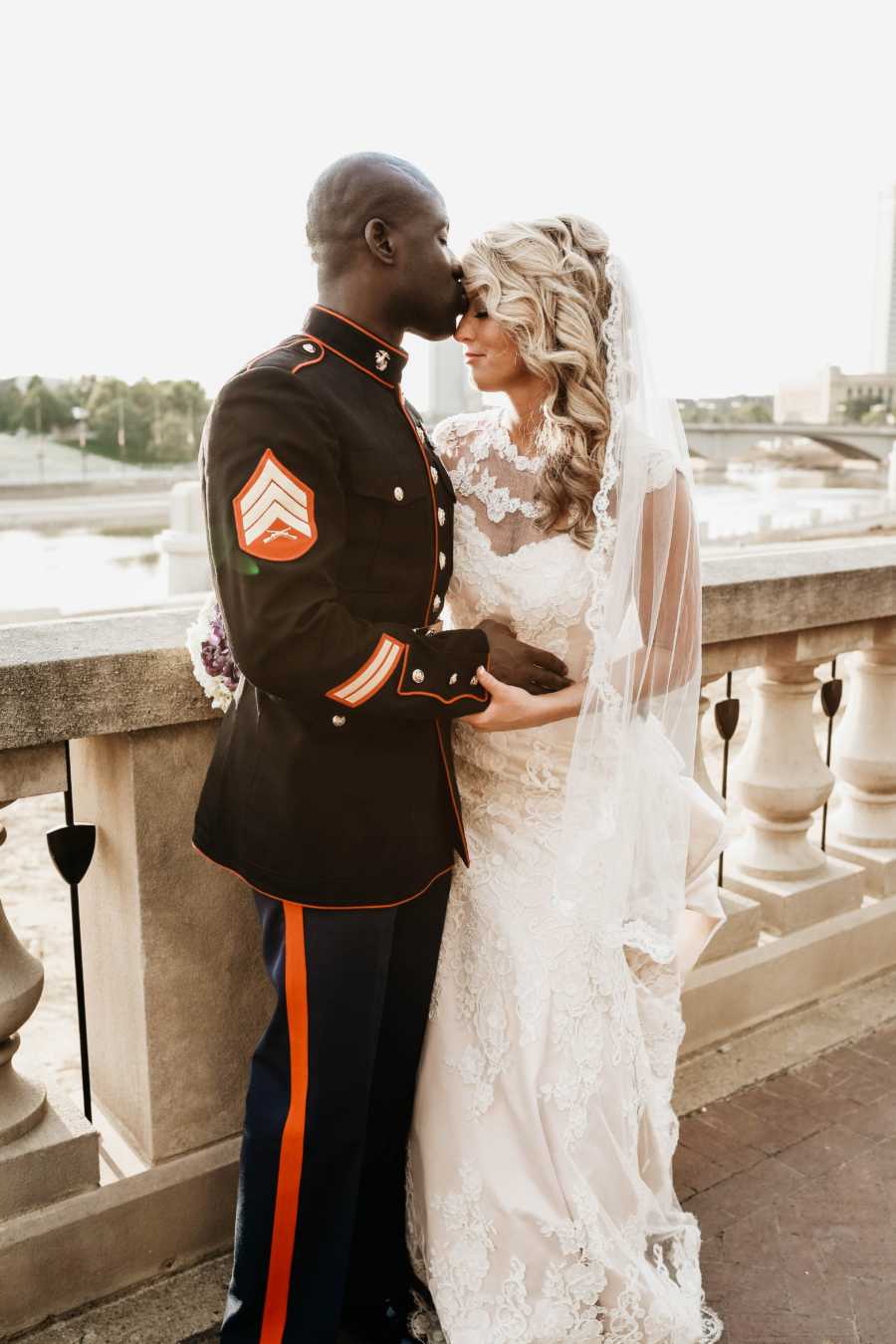 Marine groom kisses bride on forehead 