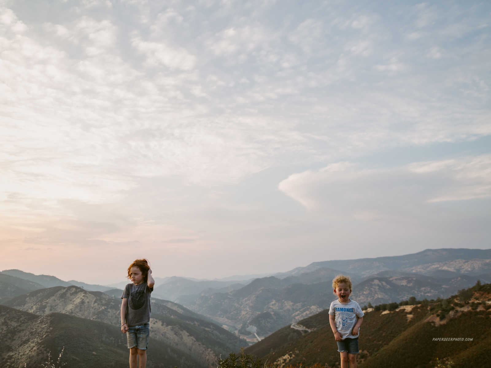 Young boy who has had two heart surgeries stands next to older brother in front of scenic view of mountains