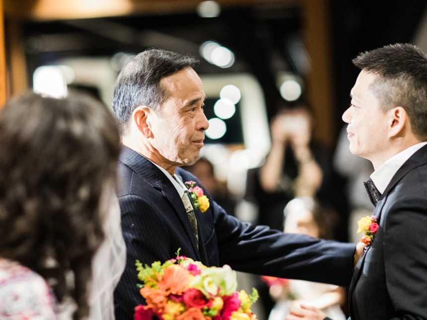 Father of terminally ill father places hand on groom's shoulder