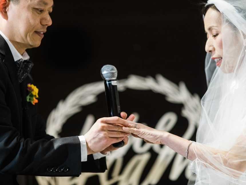 Terminally ill bride stares at hand as husband puts ring on finger 