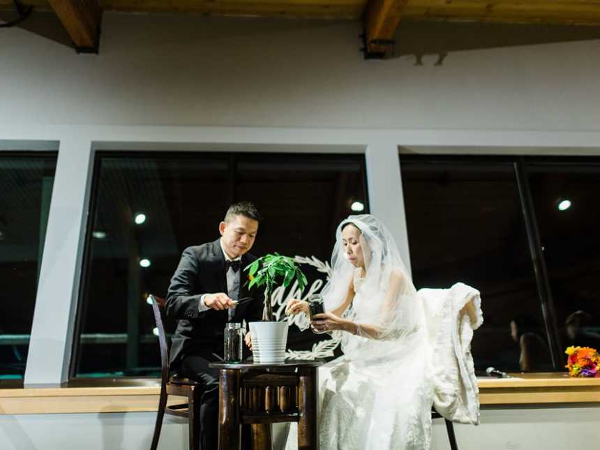 Terminally ill bride sits next to groom at small table with little plant on it