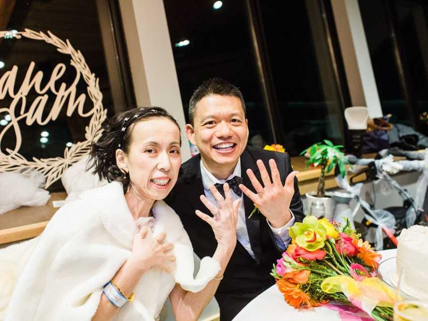 Groom and terminally ill bride smile as they hold up their ring finger hand