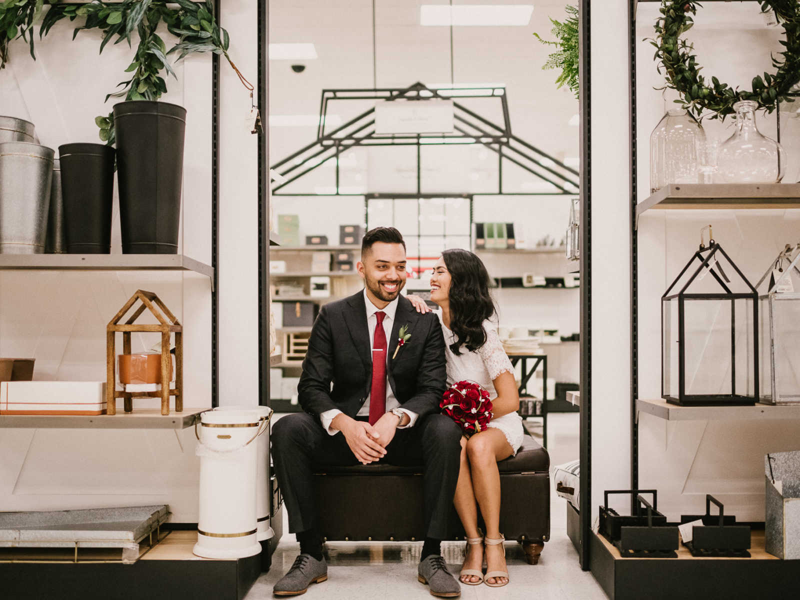 Bride and groom smiling while sitting on bench in home section of Target