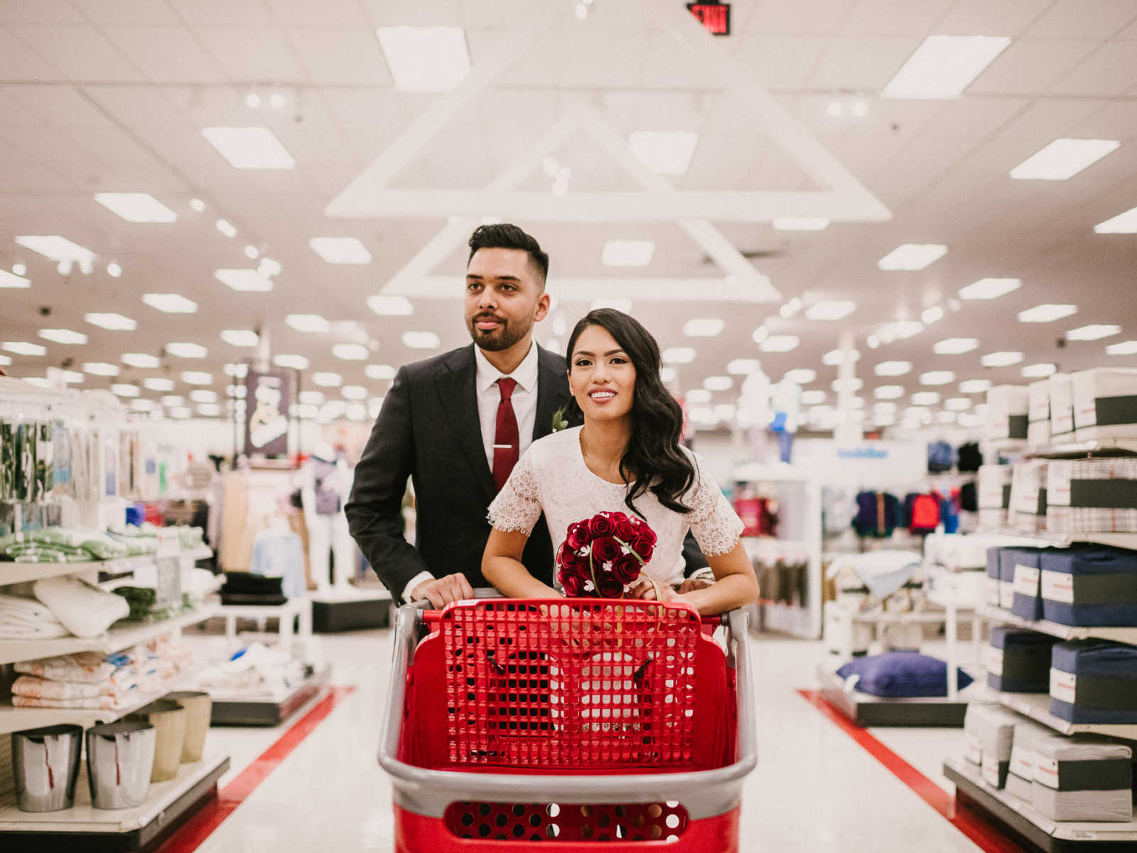 Bride and groom push shopping cart down an aisle at Target