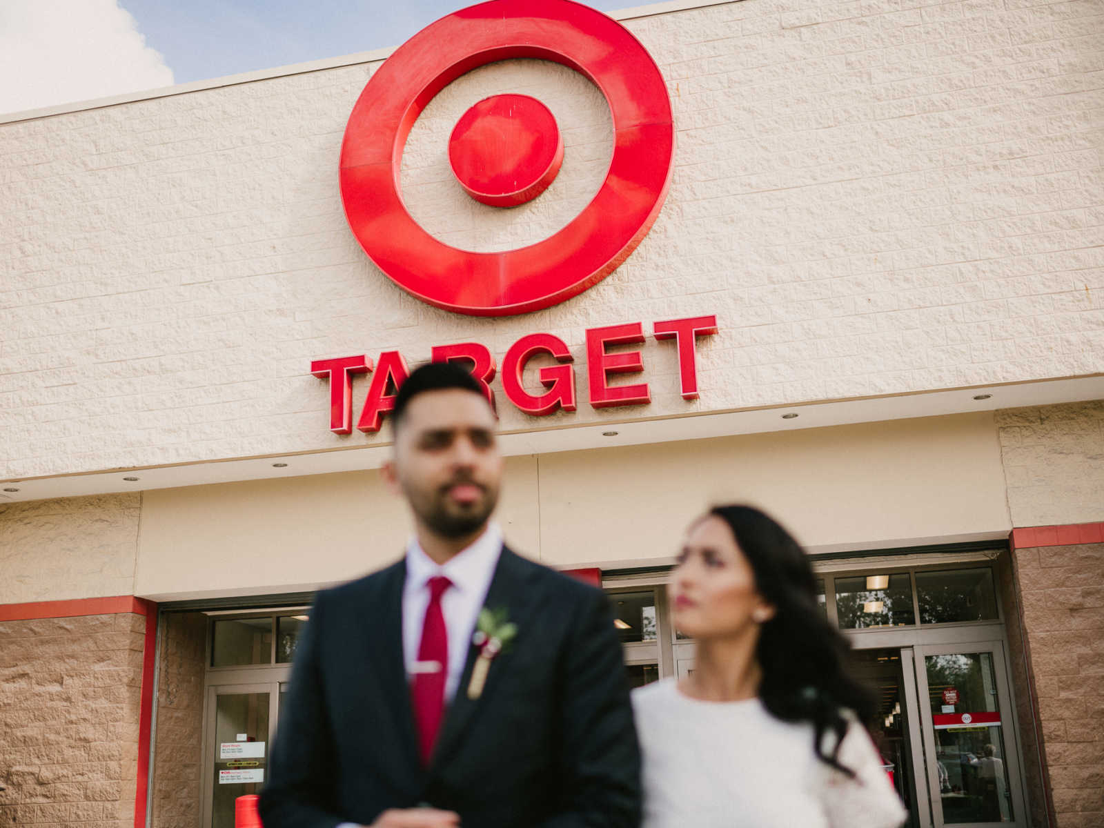 Bride looks up at groom as they are arm and arm standing outside of Target