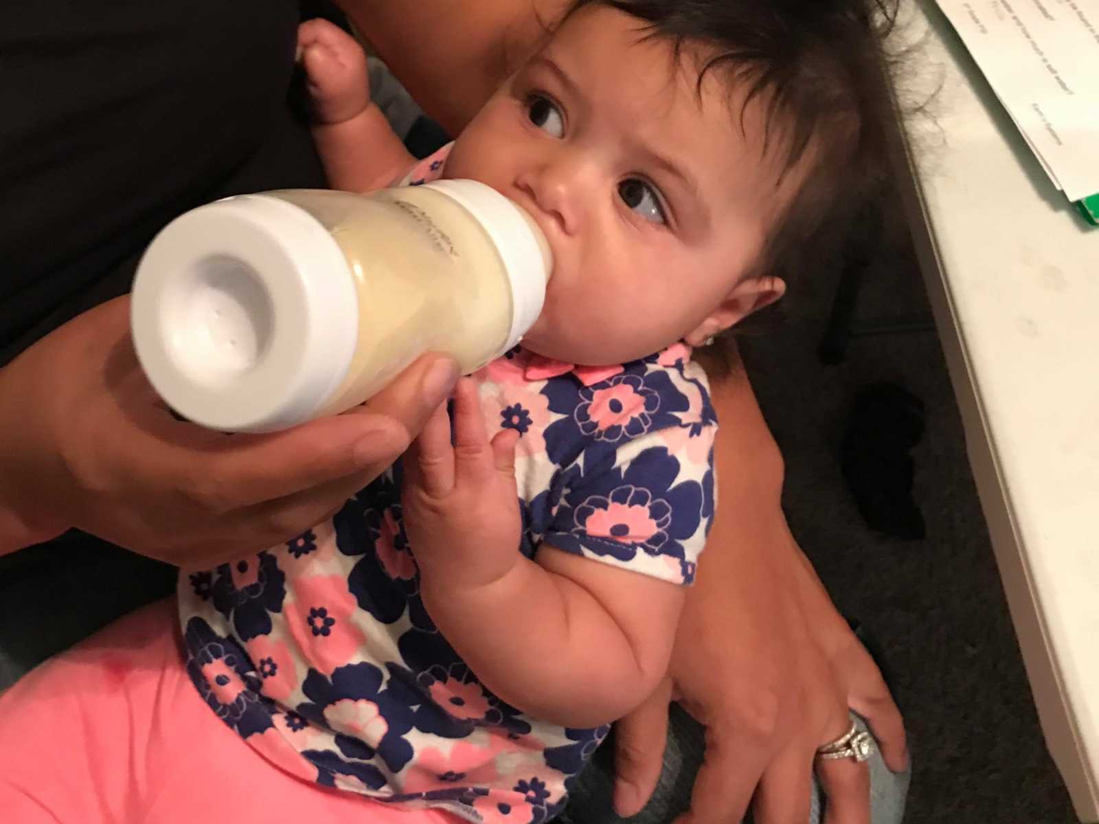 Close up of mother feeding her daughter a bottle of breastmilk that was donated 