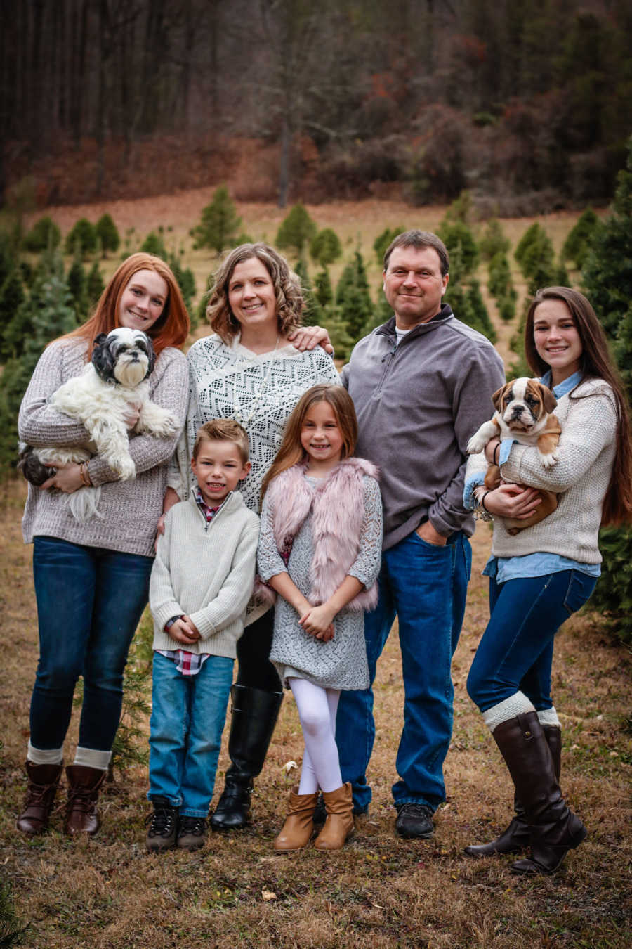 Woman who was a surrogate smiles with husband, three daughters, son and two dogs