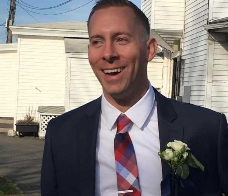 Groom smiling in suit with boutonniere of little white flowers