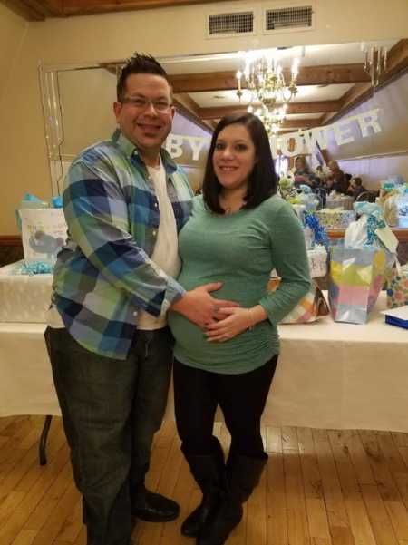 Soon to be father holds pregnant wife's stomach at baby shower