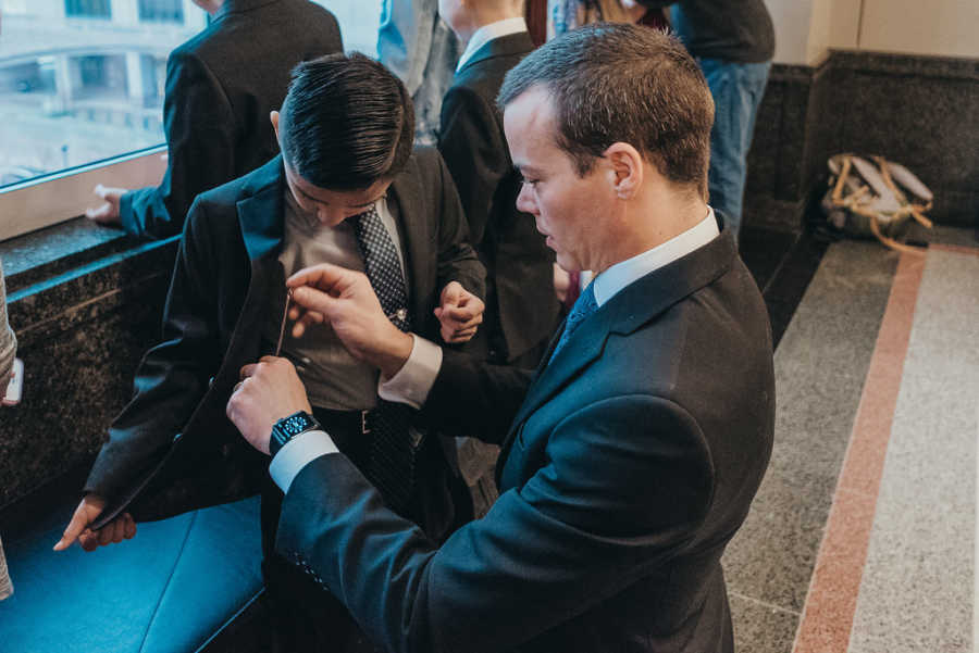 Father adjusting something in adopted sons blazer pocket