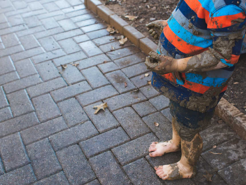 View of little boy from shoulder down covered in mud