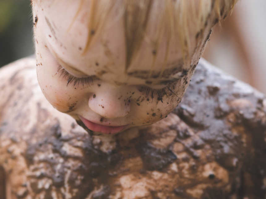 Close up of shirtless little boy covered in mud