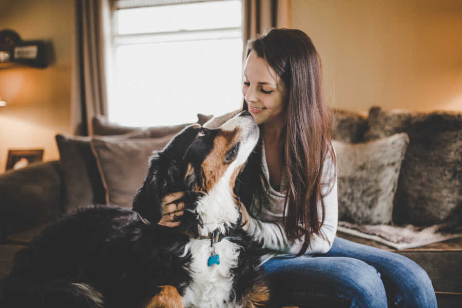 Woman sits beside sick mountain dog who is face to face with her