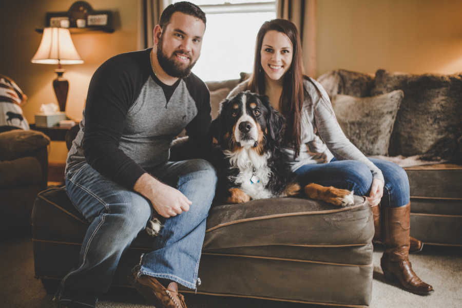 Woman and her boyfriend sit on ottoman beside sick Bernese mountain dog