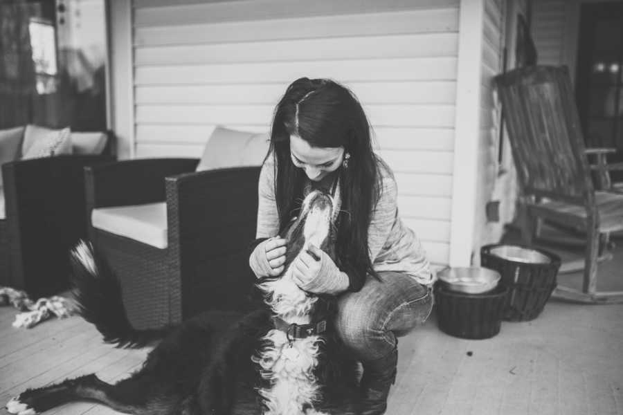 Woman crouching beside sick Bernese mountain dog who has since passed away