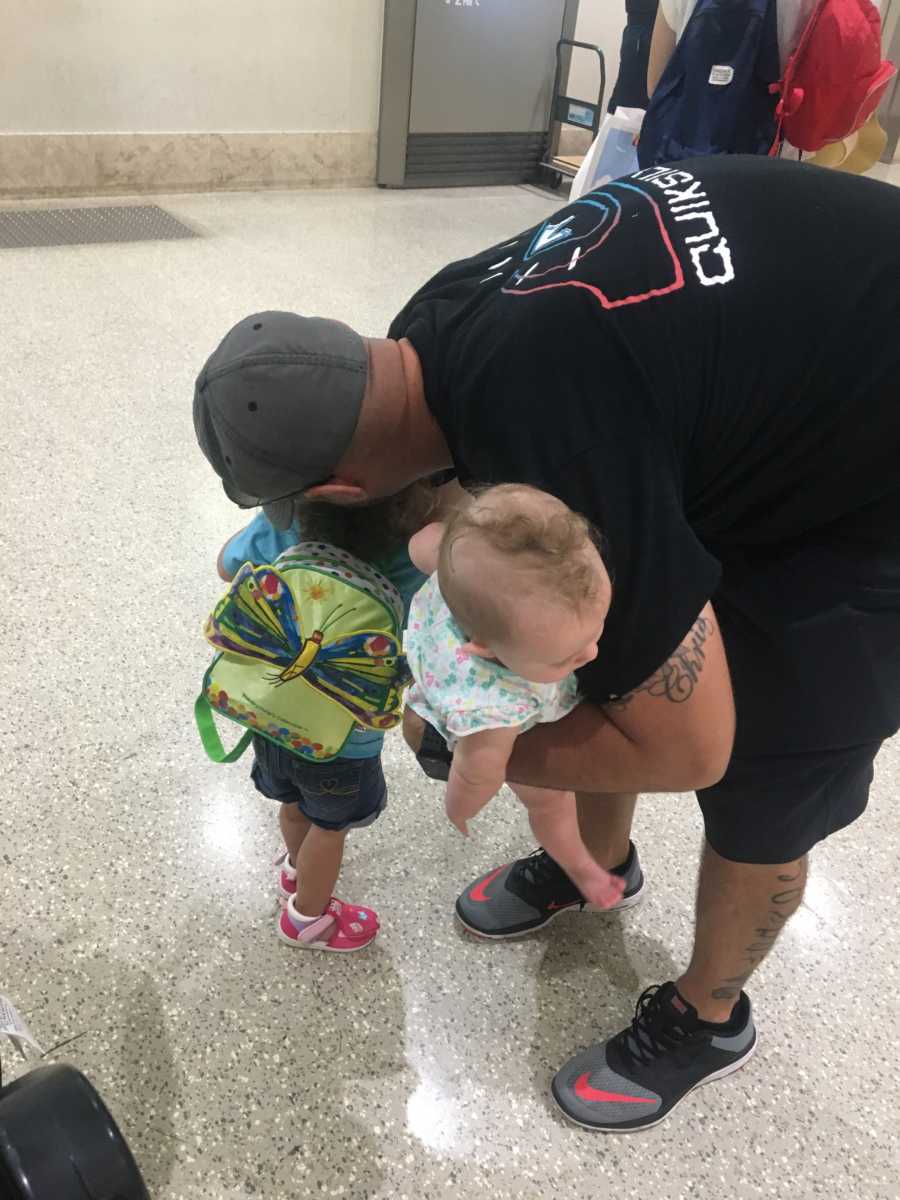 Father helping mother corral young children at airport