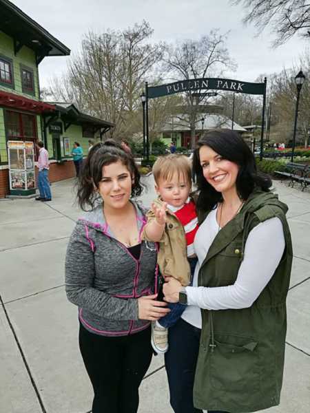 Mother holds adopted son in arm next to birth mother