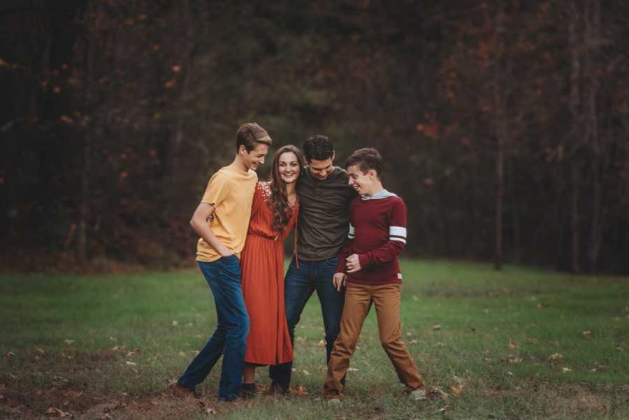 Three siblings are arm in arm with their adopted brother