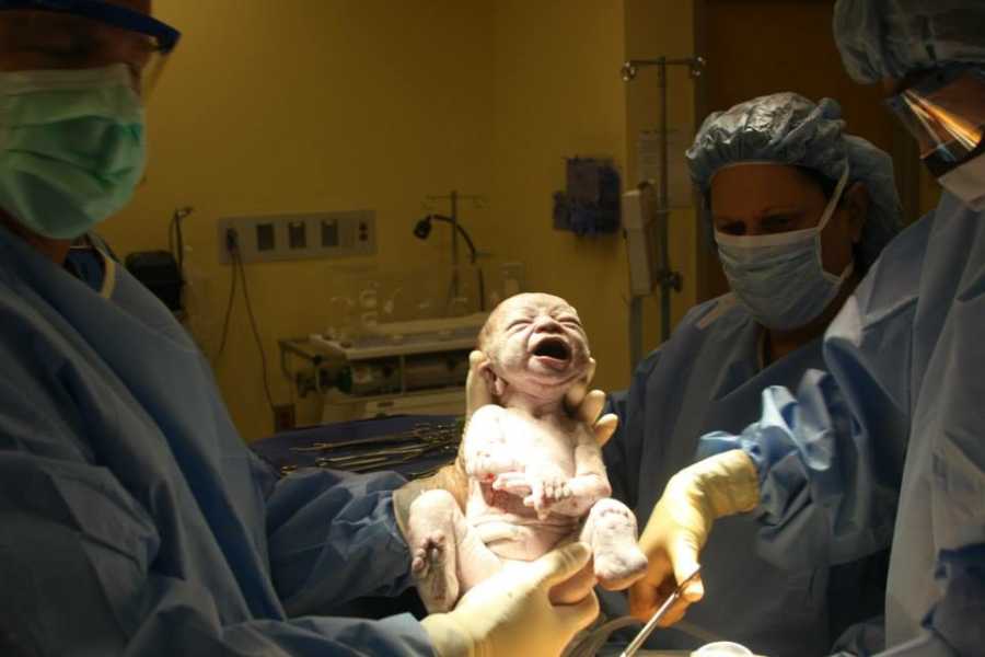 Newborn baby held by doctor who has 6 adopted siblings