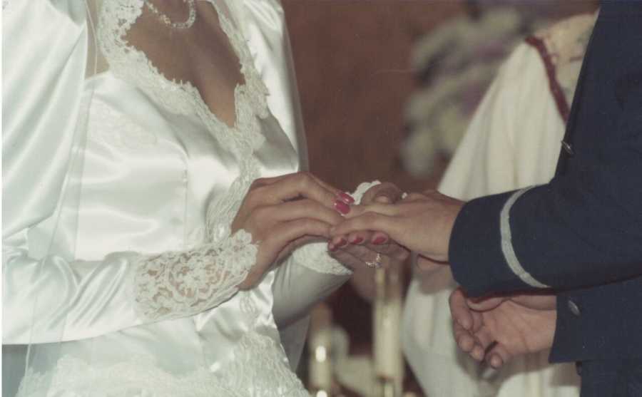 Bride placing ring on groom's finger in wedding gown her mother made for her