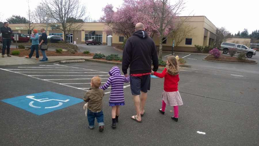 Father walking holding hands with two biological kids and foster daughter