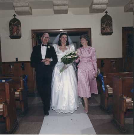 Bride walking down aisle with mother and father in dress mother sewed for her