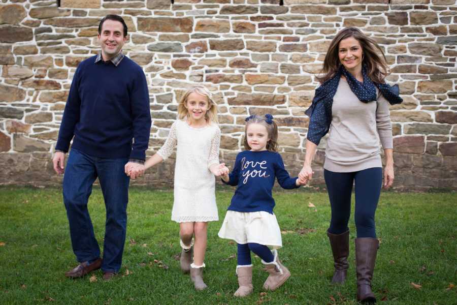 Mother and father hand in hand with oldest daughter and younger daughter with autism