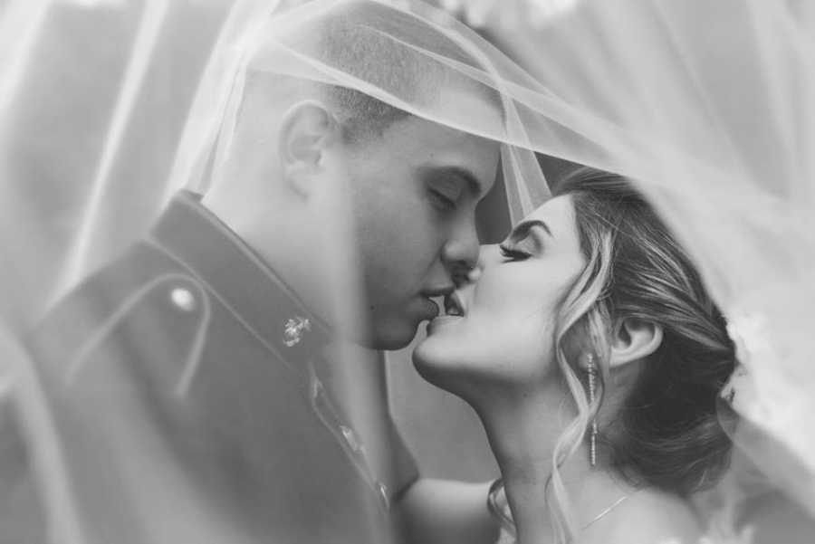 Close up of husband and wife kissing on their wedding day covered in veil 