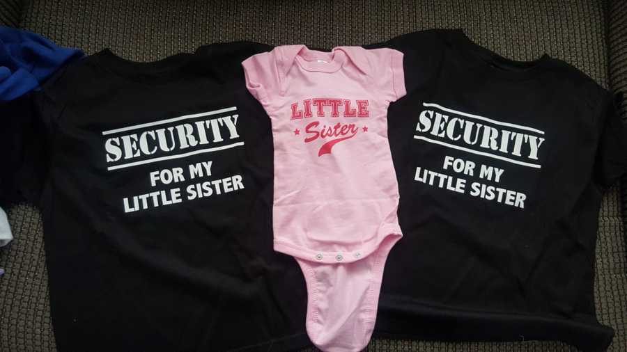 Baby pink onesie saying, "little sister" next to t-shirt's that say, "security for my little sister"