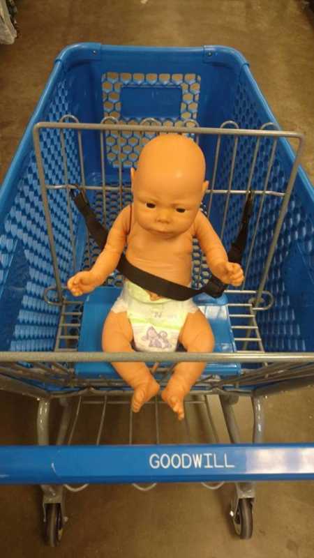 Baby doll strapped into Goodwill shopping cart