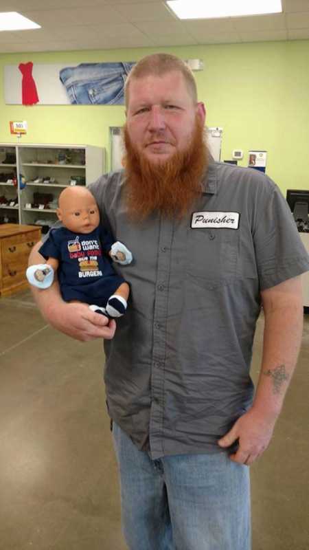Bearded man stands holding daughter's baby doll in his arms