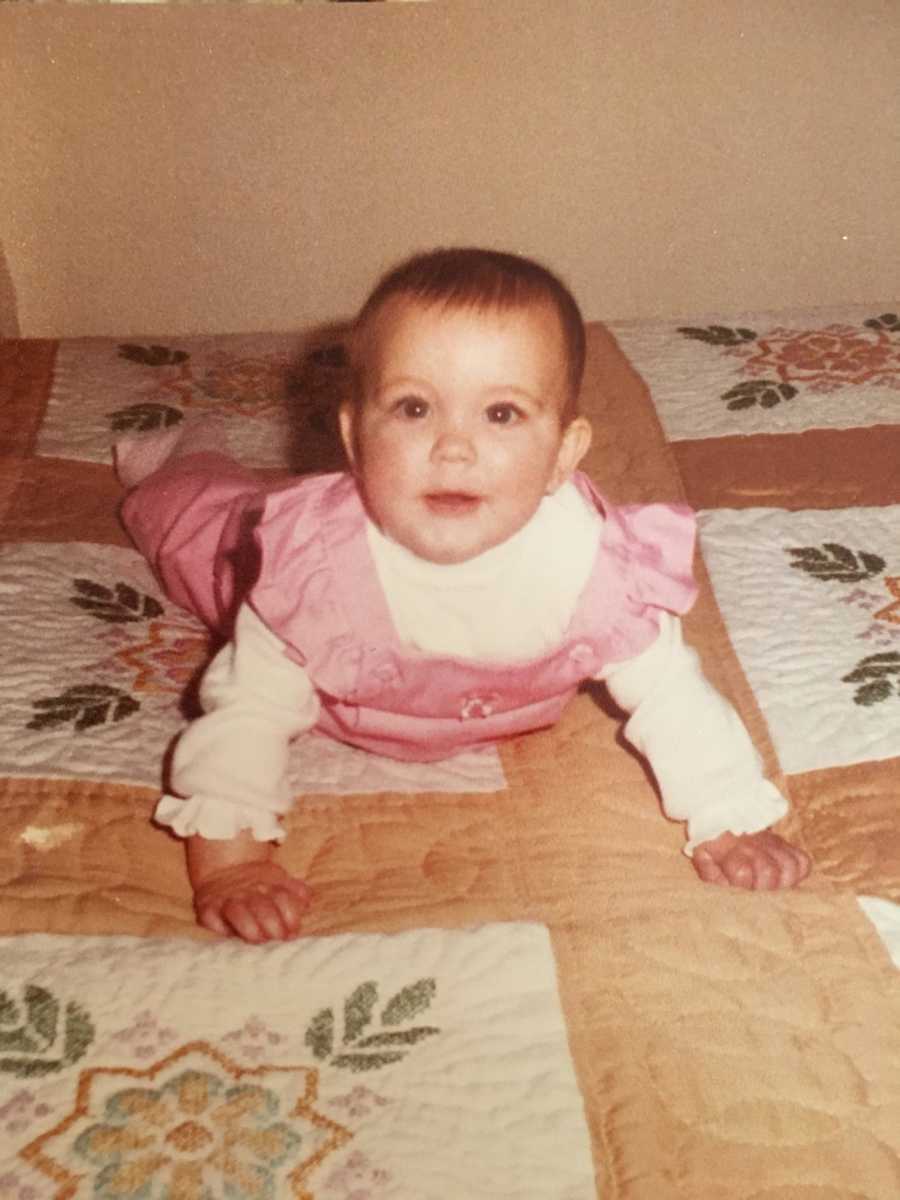 Adopted infant who is laying on bed in pink outfit