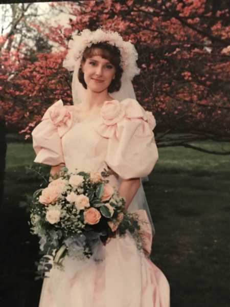 Bride stands holding bouquet of flowers in dress her mother made for her