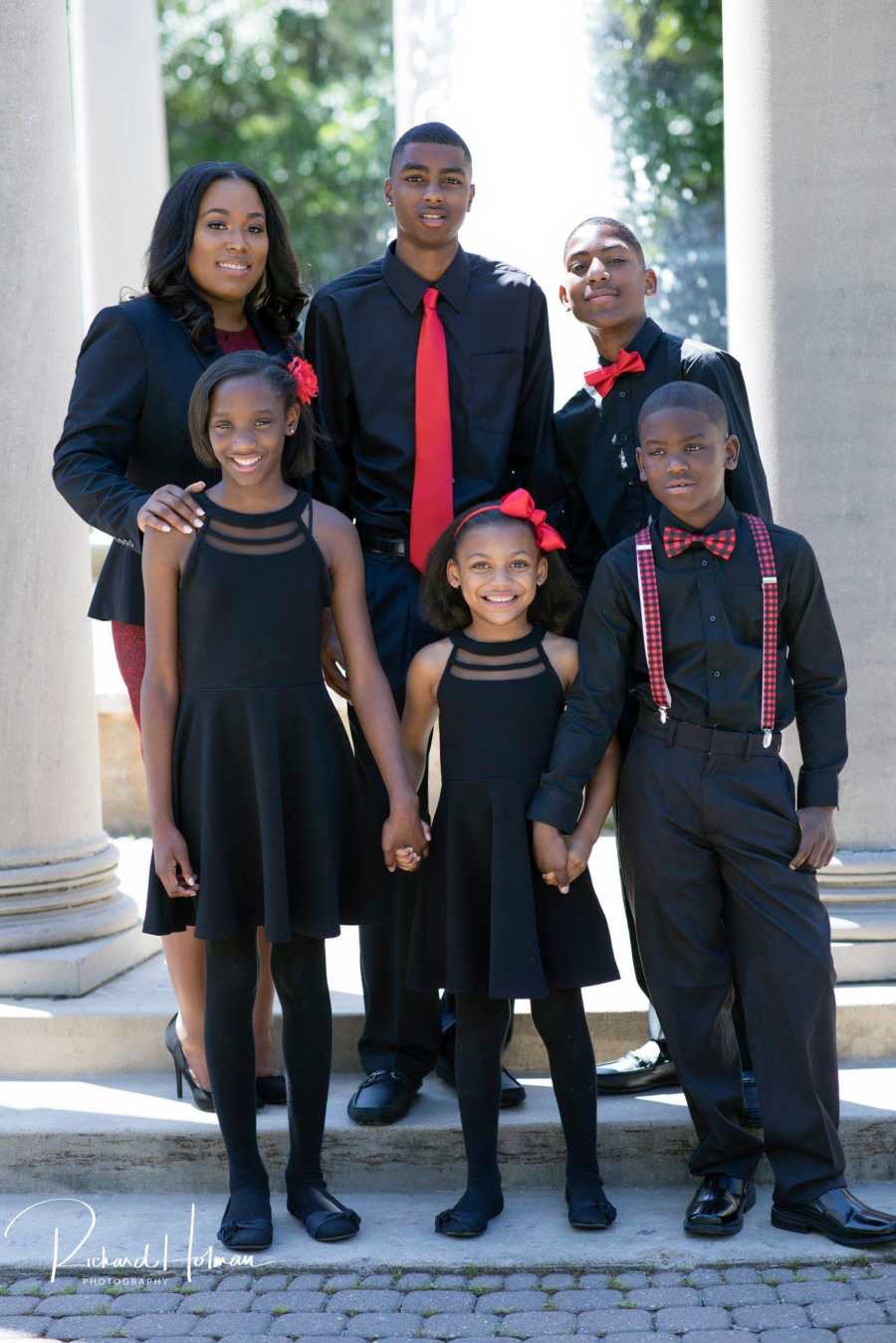 Single mother of five stands with her children smiling in formal attire