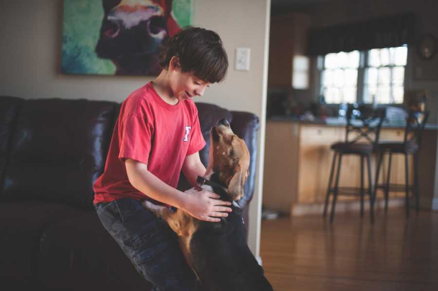 Boy who was adopted by his teacher plays with dog in new home