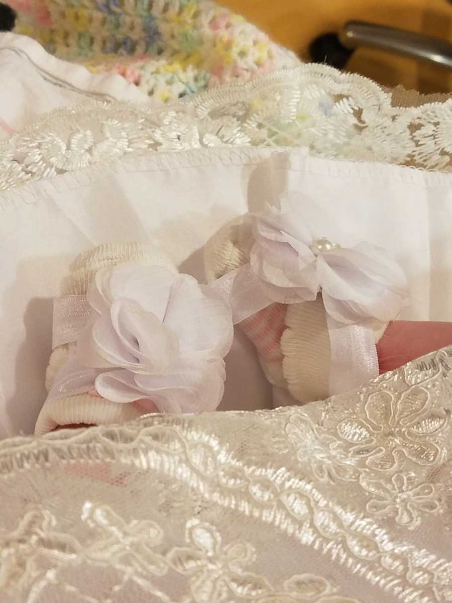 Close up of still born baby's feet with socks on with white flowers