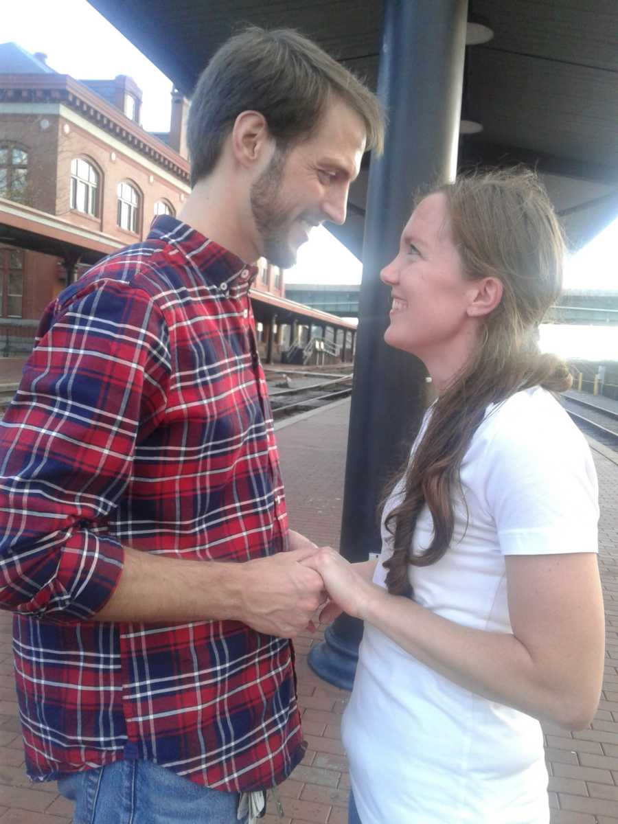 Engaged couple who haven't kissed hold hands staring into each others eyes