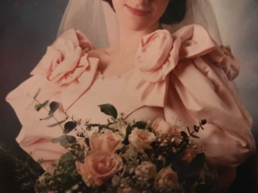 Close up of bride holding bouquet of flowers and details of dress mother made for her