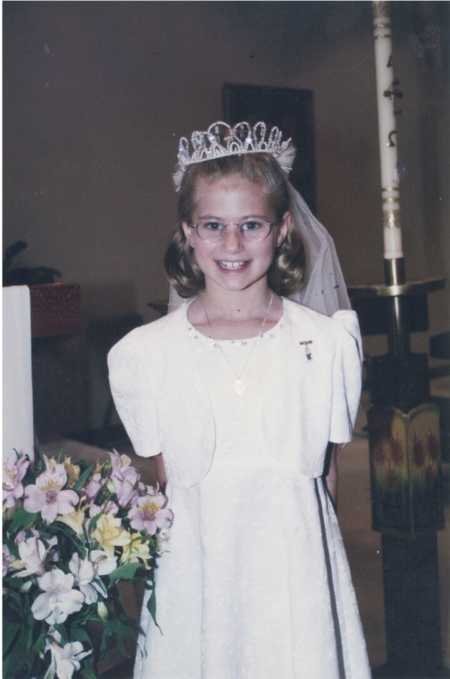 Young girl smiling in white dress woman sewed for her