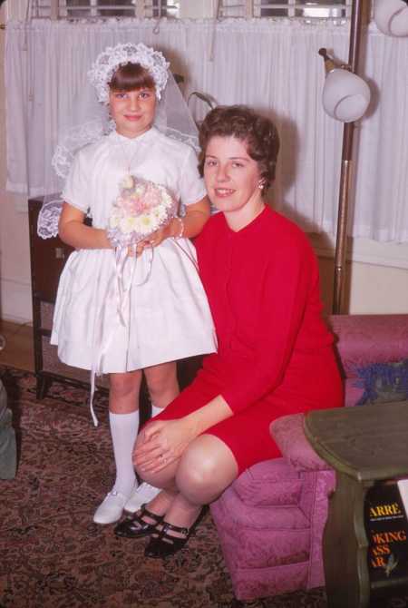 Mother sitting next to daughter in a white dress that she sewed for her daughter