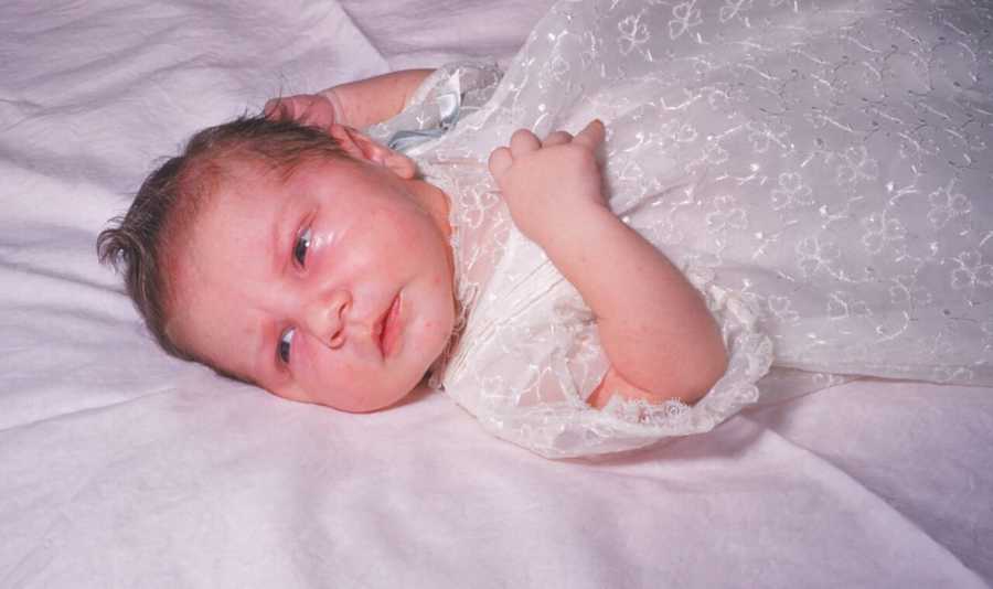 Newborn wearing christening dress her grandmother sewed for her