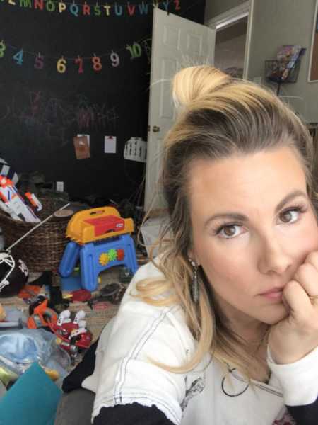 Mother who admits motherhood is hard job takes selfie in messy playroom 