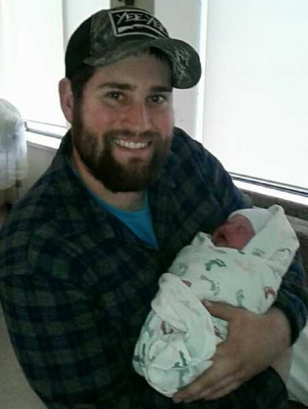 Father smiles holding albino newborn swaddled in blanket