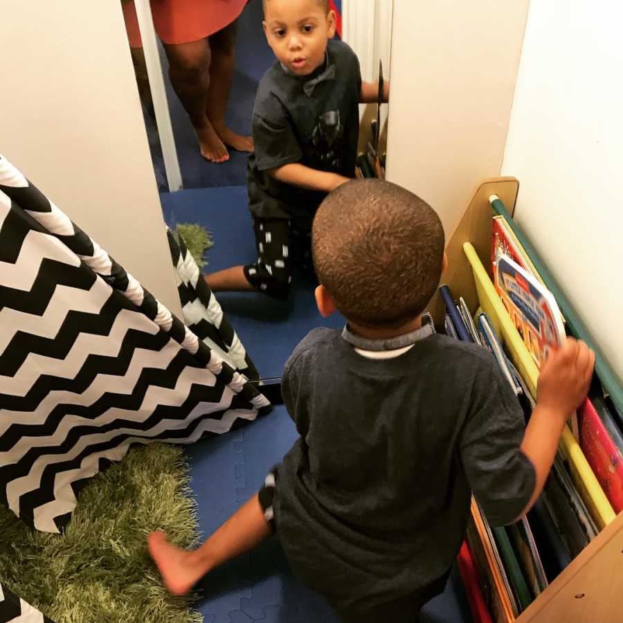 Young autistic boy sits on floor looking at himself in mirror