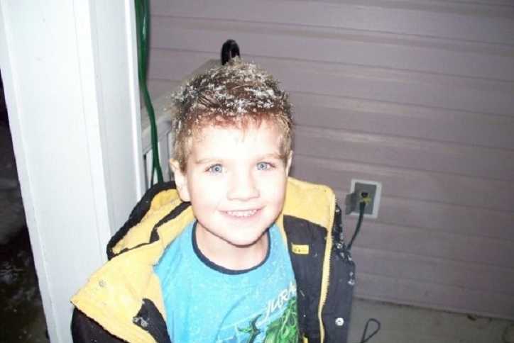 4 year old boy smiling with snow in his hair who is in foster care