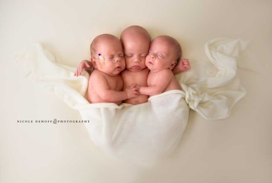 Triplets asleep in white blanket