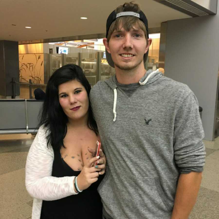 Boyfriend and girlfriend smiling arm in arm at airport